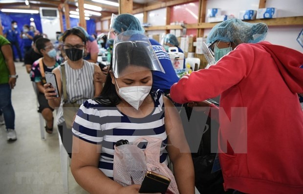 Health workers administrate COVID-19 vaccine to people in Manila, the Philippines (Photo: AFP/VNA)
