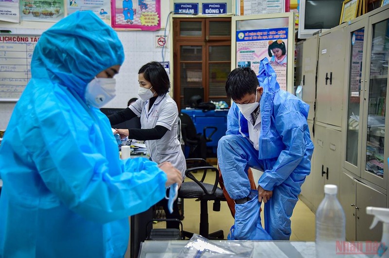 Health workers in Hang Bai Ward wear protective gear and prepare to visit people's houses for vaccination.