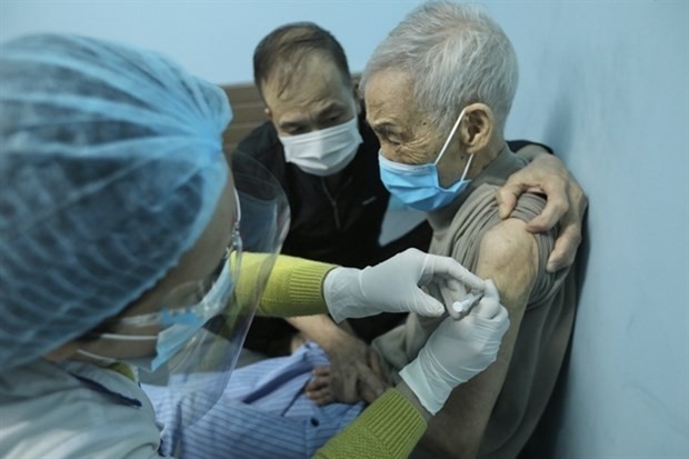 An elderly man in Hanoi is vaccinated against COVID-19 at home. Vaccination coverage is one of the criteria for the assessment of pandemic risk levels. (Photo: VNA)