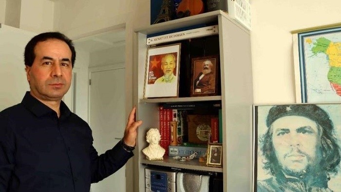Ahmet Yazar standing next to a portrait of President Ho Chi Minh placed on his bookcase (Photo: VNA)