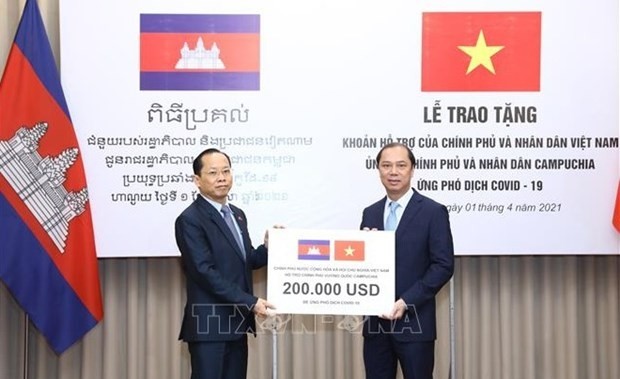 Deputy Minister of Foreign Affairs Nguyen Quoc Dung (R) symbolically presents Vietnam's assistance for Cambodia in the COVID-19 fight on April 1, 2021. (Photo: VNA)