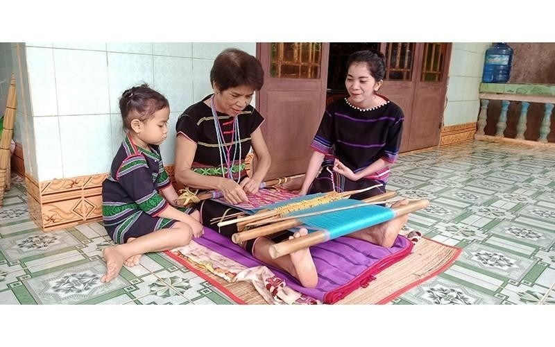 Artisan Thi An De (Tho Son Commune, Bu Dang District, Binh Phuoc Province) transfers her knowledge of traditional brocade weaving to her descendants. (Photo: NHAT SON)