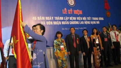 Vice President Nguyen Thi Doan pins the Labour Order, second class, onto the hospital’s traditional flag (Source: qdnd.vn)