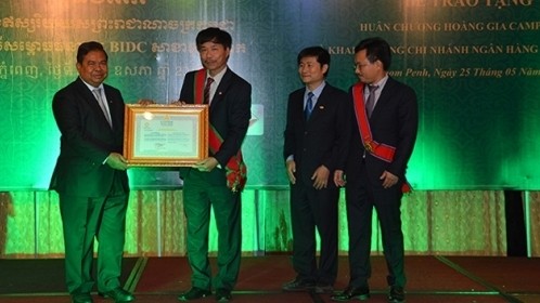Governor of the National Bank of Cambodia Chea Chanto (left) grants the certificate of establishment of the Toul Kork-branch bank to a representative from BIDC