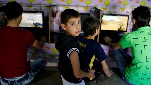 A Syrian boy gestures as his friends play video games at the Harran refugee camp in the Sanliurfa province, Turkey, June 6, 2016. (Credit: Reuters)
