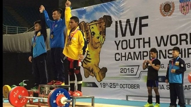 Le Nguyen Quoc Bao (centre) and his two runners-up on a podium receiving their medals of the International Weightlifting Federation Youth World Championship in Malaysia. ​(Source: VNA)