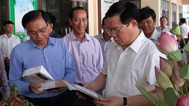 Deputy PM Vuong Dinh Hue looks at some products of local agricultural cooperatives.