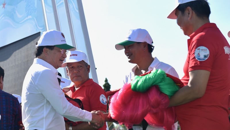 Deputy PM Trinh Dinh Dung (L) presents national flags and fishing nets to fishermen at the launch of Vietnam Seas and Island Week 2019 in Bac Lieu on June 1. (Photo: VGP)