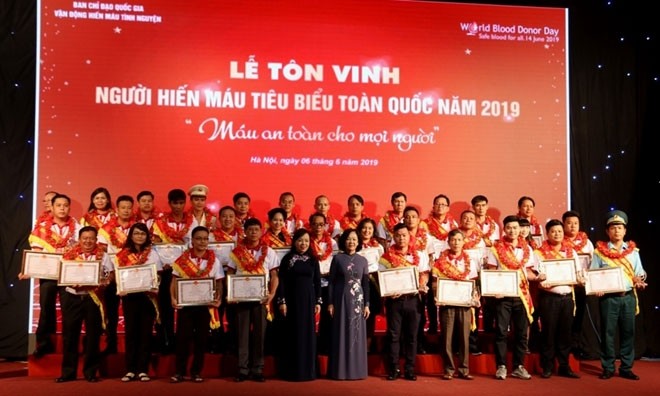 Politburo member Truong Thi Mai and Minister of Health Nguyen Thi Kim Tien presents certificates of merit to the outstanding blood donors.