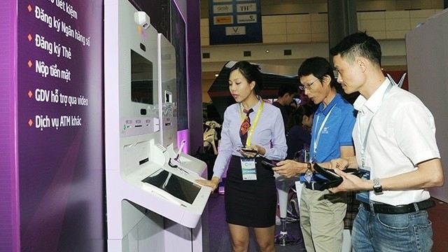 A female staff member of Tien Phong Bank (L) introduces digital technology services to visitors at the Vietnam Private Sector Economic Forum 2019 in early May this year. (Photo: NDO/QUANG MINH)