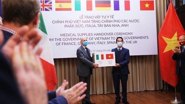 Vietnamese Deputy Foreign Minister To Anh Dung (R) handed a symbolic token representing the gift of 111,000 anti-bacterial masks from the Vietnamese Government to Italian ambassador Antonio Alessandro, Hanoi, April 7, 2020. (Photo: VNA)