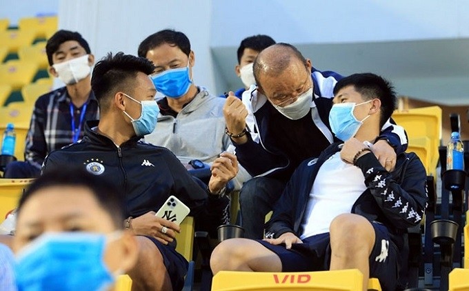 Vietnam head coach Park Hang-seo (second from right) speaks to national team defender Tran Dinh Trong in the stands during a V.League 2020 match. 