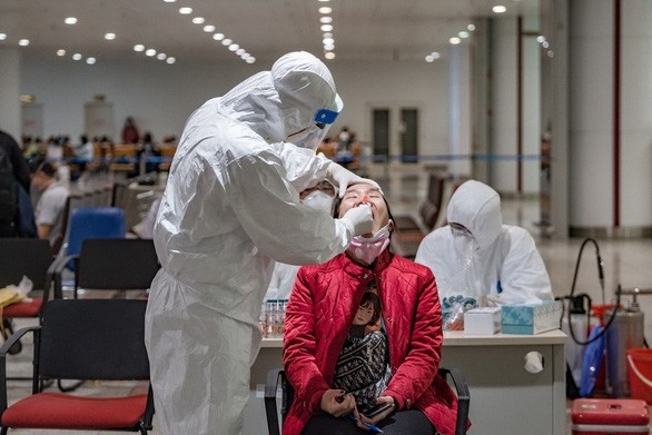 A medical worker takes a sample from a woman for COVID-19 testing at Noi Bai International Airport in Hanoi. (Photo: tuoitre.vn)