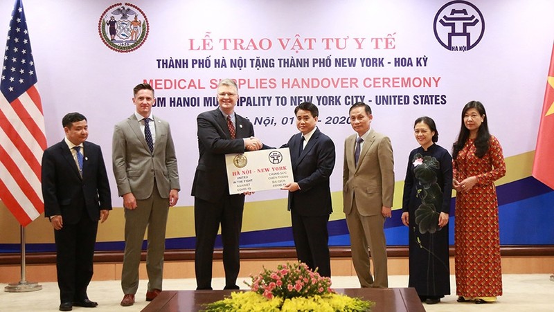 Chairman of Hanoi municipal People’s Committee Nguyen Duc Chung presents masks to representatives of New York. (Photo: HNMO)