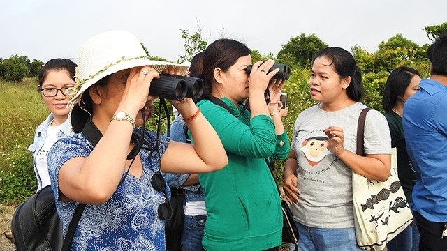 Le Thi Trang (right) guiding people to observe doucs through binoculars. 