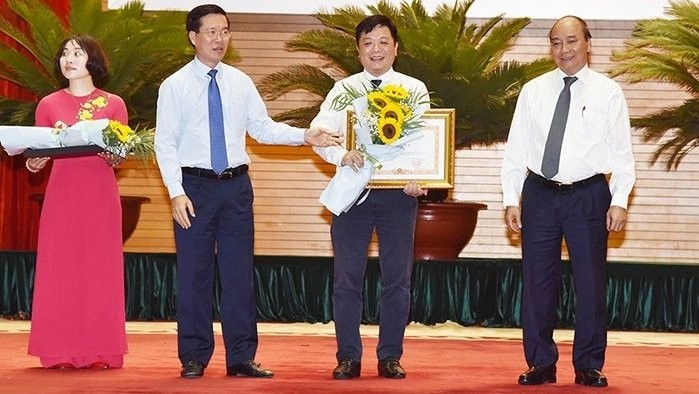 PM Nguyen Xuan Phuc (right) and Politburo member, Secretary of Party Central Committee and Head of the PCC's Commission for Communication and Education, Vo Van Thuong, present the PM's certificate of merit to Nhan Dan (People) Newspaper.