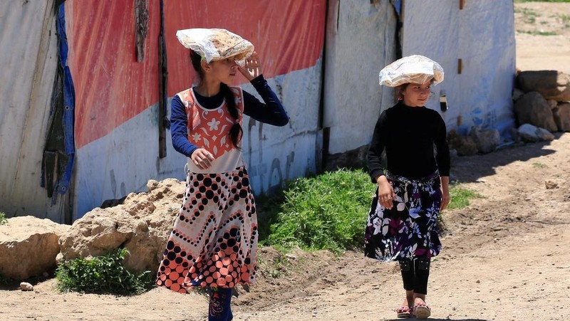 Syrian refugee girls carry stacks of bread on their heads at a Syrian refugee camp in the Bekaa valley, Lebanon, May 7, 2020. (Photo: Reuters) 