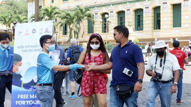 A staff of Ho Chi Minh City’s tourism sector delivers free face masks to visitors in the city (Photo: VGP)