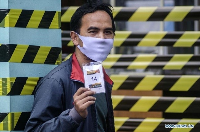 A volunteer shows a number card before participating in a vaccine clinical trial at Garuda clinic in Bandung, West Java, Indonesia, Aug. 14, 2020. Indonesian President Joko Widodo has expressed his hope that the third phase of the clinical test on anti-coronavirus vaccine would be completed within six months. (Photo: Xinhua)