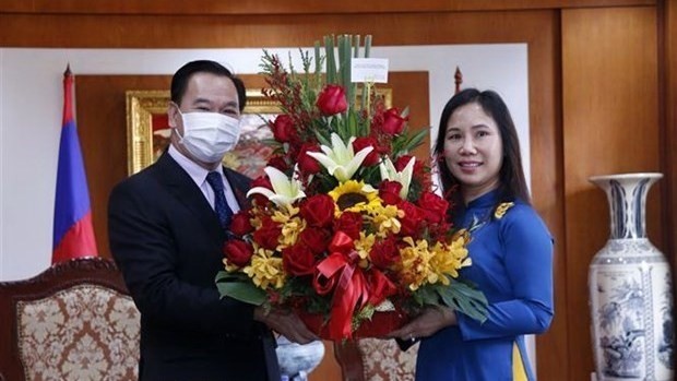 Thongsalith Mangnomek (R), Secretary of the Lao People’s Revolutionary Party (LPRP) Central Committee and Head of the LPRP Central Committee's Office, presents congratulation flowers to Chargé d'affaires a.i. of the Vietnamese Embassy Trinh Thi Tam on February 3 (Photo: VNA)