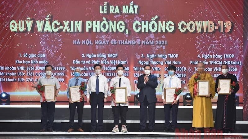 Prime Minister Pham Minh Chinh (fourth from right) presents flowers and certificates of merit to donors at the inaugural ceremony of National COVID-19 Vaccine Fund. (Photo: NDO)